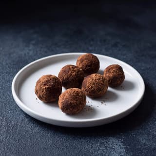 Cocoa-dusted chocolate truffles on navy slate — slate background chocolate food photography