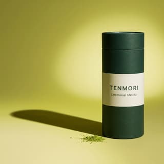 Lata de matcha sobre um fundo contínuo verde-amarelado, com uma sombra longa — fotografia de produto para conteúdo A+ da Amazon