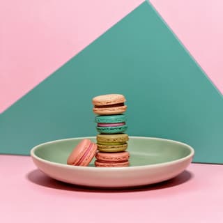 Stack of pastel French macarons on a pink studio set — patisserie food photography