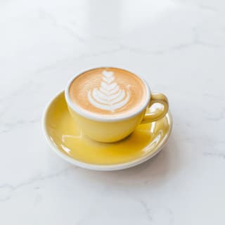 Cappuccino with rosetta latte art on white marble — café coffee menu drink photography