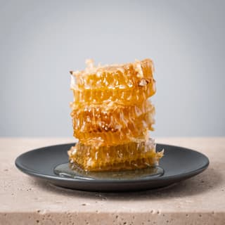 Stacked raw honeycomb on a dark plate on travertine — specialty producer poster photography