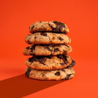 Stacked chocolate chunk cookies on tangerine orange — price promo poster food photography