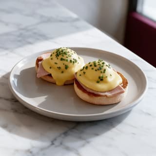 Eggs Benedict with hollandaise on a white marble table — hotel breakfast food photography