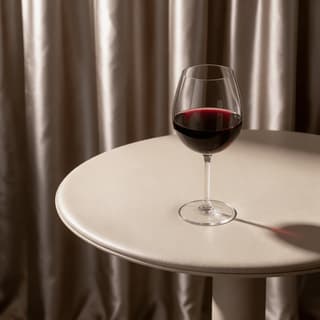 Glass of red wine on a cream pedestal table — hotel wine list photography