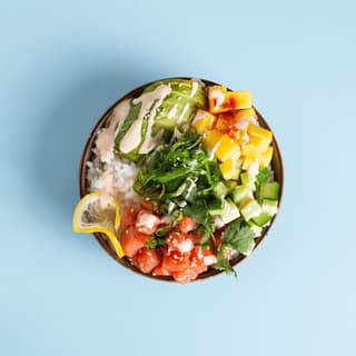 Salmon poke bowl with mango on pastel blue — delivery app header food photography