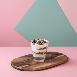 Blueberry yogurt parfait in a glass on pink — cafe brand banner food photography
