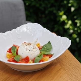 Burrata with tomatoes and basil in a white bowl — restaurant group food photography