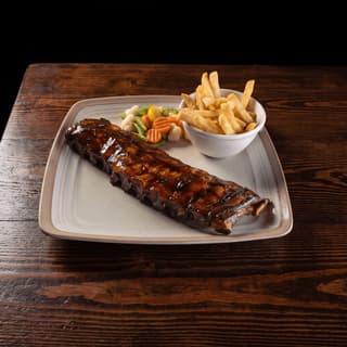 Barbecue-glazed pork ribs with fries on a stoneware plate — smokehouse grill food photography