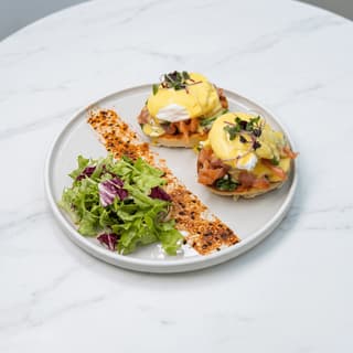 Eggs Benedict with smoked salmon and hollandaise on white marble — brunch menu food photography