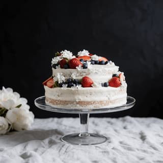 Berry-topped semi-naked layer cake on a glass cake stand — home baker food photography