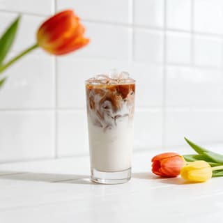 Iced latte with a milk swirl on a white counter — coffee shop food photography