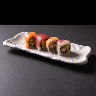 Rainbow sushi rolls topped with salmon, tuna and shrimp on dark stone — sushi ad photography
