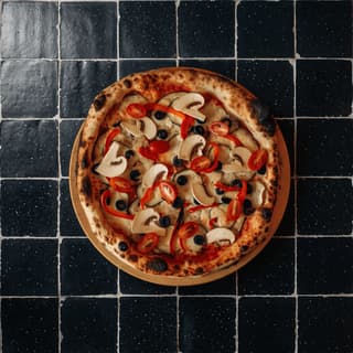 Wood-fired pizza with blistered crust on black tile from above — pizzeria ad photography