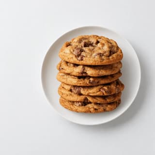 Stack of five brown-butter chocolate chunk cookies with flaked sea salt on a seamless white background