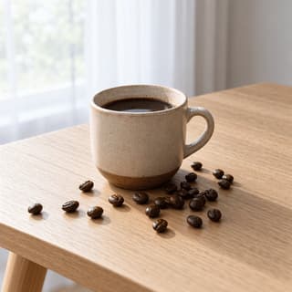 Speckled stoneware mug of black coffee beside a scatter of roasted whole beans in soft window light