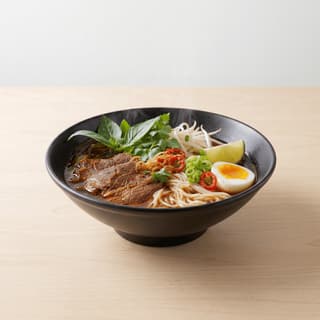 Pan-asian fusion noodle bowl broth chili oil herbs lime soft egg bowl — fusion noodle hero photography