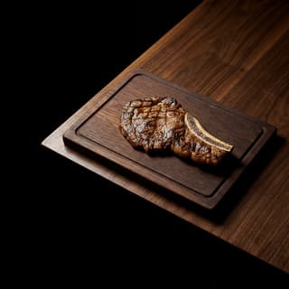 Massive dinosaur-sized beef plate rib with pepper bark and half-inch smoke ring on charred wooden plank — New York smokehouse BBQ photography
