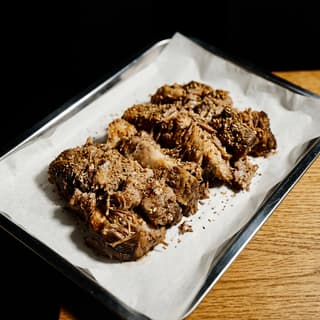 Kansas City burnt ends cubes piled on paper deli boat with paintbrush sauce smear — classic American BBQ photography