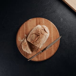 Sourdough cross-section showing dramatic open crumb alveoli on dark slate — bread photography macro