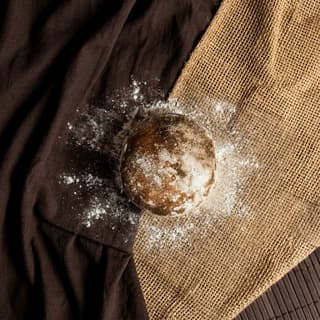 Fresh country miche with visible oven steam on flour-dusted linen — artisan bread photography