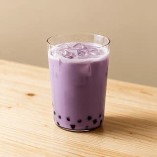 Iced taro milk tea in a clear glass showing a smooth pale purple body over a bed of dark tapioca pearls