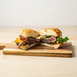 Smash burger cross section sliced wooden board layers visible — burger cross section hero photography