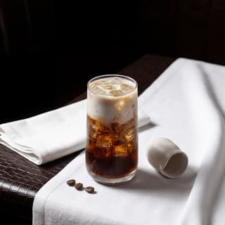 Iced latte tall glass milk pour swirl light brown coffee — iced latte hero photography