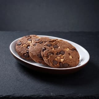 Oversized chocolate chip walnut cookie with molten gooey center — American bakery cookie photography