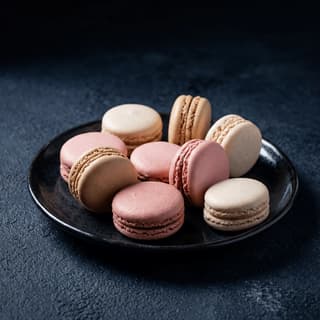 Rose macarons with raspberry and lychee ganache on dark slate — French macaron photography