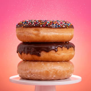Triple stacked glazed donut tower chocolate icing rainbow sprinkles — donut shop hero photography