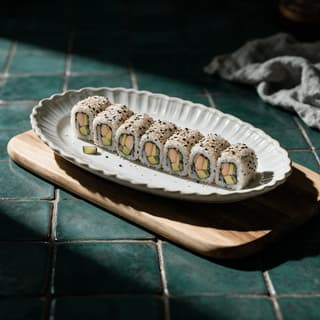 Tám miếng california roll cắt đều thành khoanh tròn lộ ra thịt cua bơ và dưa chuột với mè