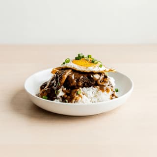 Loco moco rice hamburger patty egg gravy plate light wood — loco moco hero photography