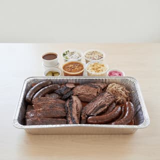 Houston BBQ-bræt med brisket, ribs, pølse, bagepapir, pickles og løg — BBQ-bræt-hero-fotografering