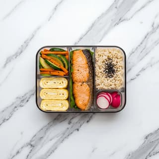 Bento box compartmentalized lacquer rice protein tamagoyaki pickles overhead — bento hero photography