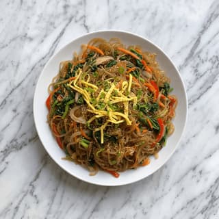 Japchae glass noodles sweet potato vegetables sesame overhead colorful plate — japchae hero photography