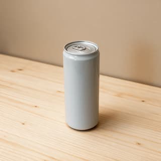 Single unbranded slim silver drink can standing alone on a pale wood counter