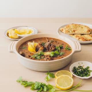 Nihari beef shank bone marrow rich red brown gravy ginger lime fried onion bowl — nihari hero photography