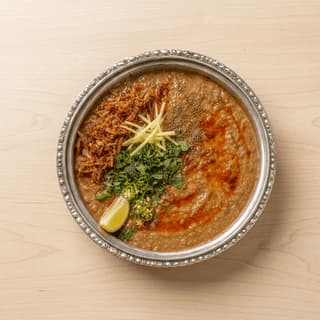 Haleem lentil wheat meat porridge fried onion ginger lime cilantro chaat masala overhead bowl — haleem hero photography