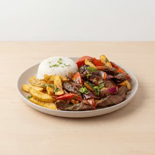 Lomo saltado beef stir fry onion tomato fries plate — lomo saltado hero photography