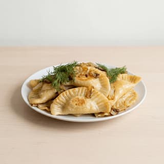 Pierogi golden butter fried caramelized onion sour cream pleated edge plate — pierogi hero photography