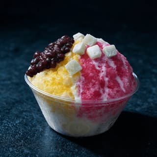 Wide cup of shave ice built over vanilla ice cream and topped with soft mochi and sweet red beans