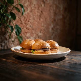 Mini beef sliders with melted cheddar and burger sauce clustered on a dark wood table for late night service