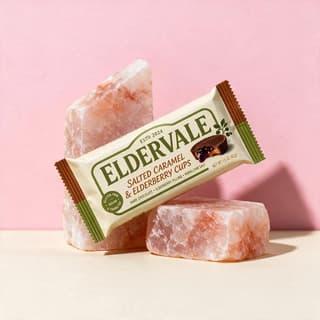 Peanut butter cups pack balanced on pink salt blocks against pastel backdrop — minimal CPG campaign photography