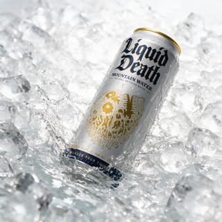 Canned water crashing into crushed ice with splash — high-key beverage product photography