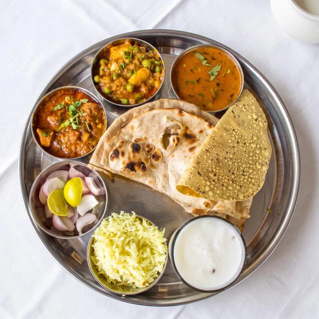 Indian thali platter steel bowls curries rice dal naan rice overhead — thali hero photography