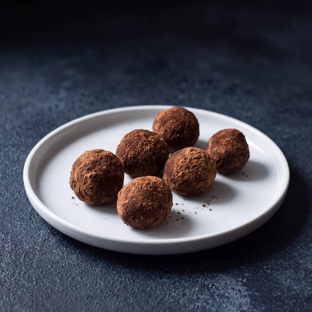 Cocoa-dusted chocolate truffles on navy slate — slate background chocolate food photography