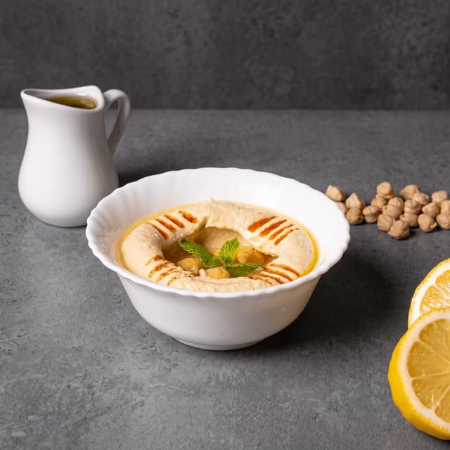 Humusas su alyvuogių aliejumi, avinžirniais ir paprika ant pilko betono — užtepėlių prekės ženklo maisto fotografija