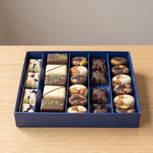 Open blue gift box of assorted nut chocolates on pale oak — chocolatier gift photography