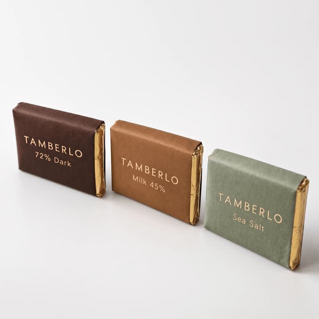 Three wrapped craft chocolate bars standing on seamless white — webshop packshot photography