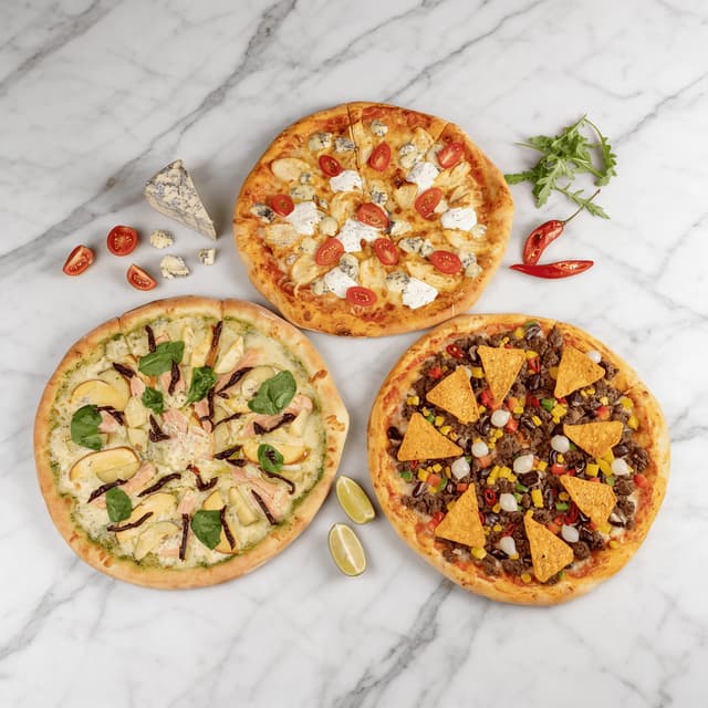 Three loaded pizzas from overhead on white marble — pizza menu campaign food photography